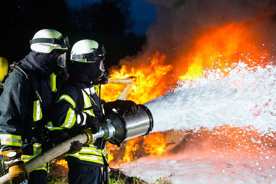 Firefighter - Firemen extinguishing a large blaze, they are standing with protective wear in front o